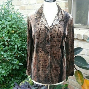 May include: A long-sleeved button-up shirt with a brown and black abstract print. The shirt is made of a soft, velvety material.