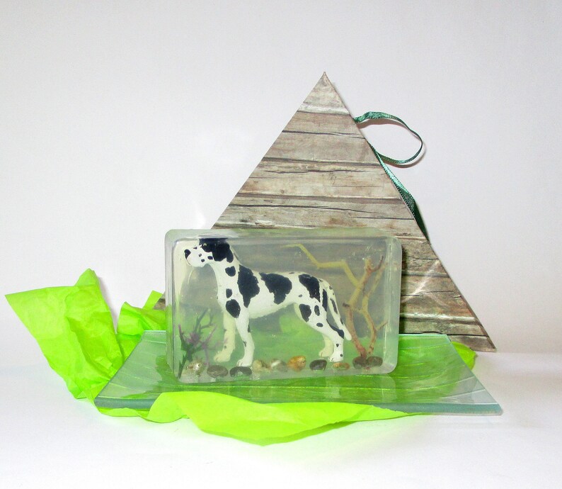 Puede incluir: Una barra de jab&oacute;n rectangular transparente con una figurita de perro d&aacute;lmata en blanco y negro en su interior. La barra de jab&oacute;n est&aacute; sobre una superficie de vidrio transparente y verde.