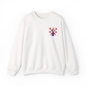 Könnte beinhalten: Ein weißes Sweatshirt mit Rundhalsausschnitt und langen Ärmeln. Ein kleines Wappen mit einem rot-weiß karierten Muster und einer Figur in Blau und Weiß befindet sich auf der oberen linken Brust.