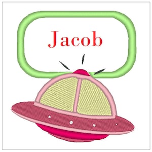 Puede incluir: Un óvalo verde con el nombre Jacob en texto rojo sobre una nave espacial de dibujos animados rosa y amarilla.