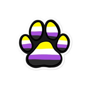Peut inclure: Un autocollant en forme de patte de couleur jaune, blanc, violet et noir, représentant le drapeau de la fierté non binaire.