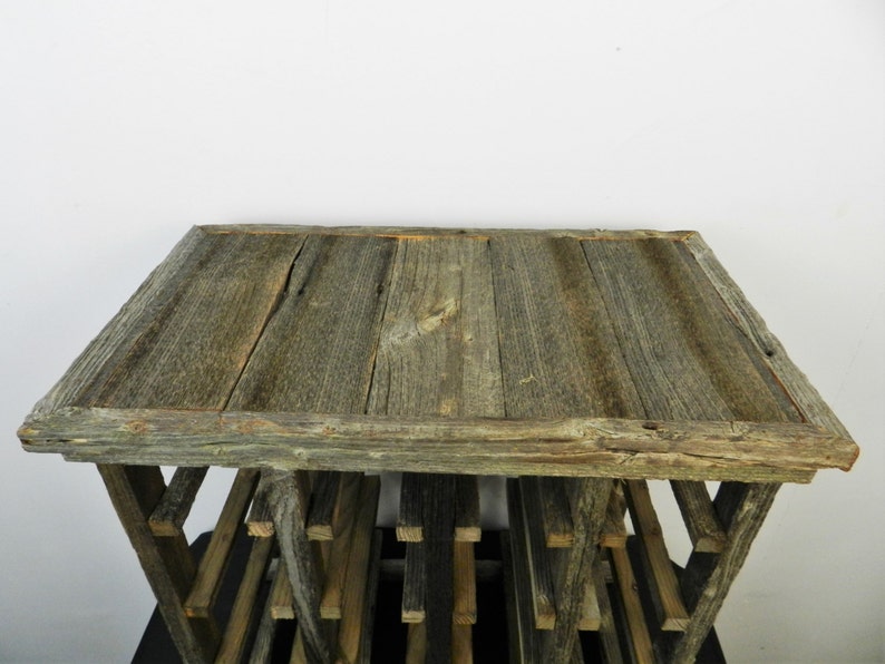Puede incluir: Estante de vino de madera r&uacute;stica con una parte superior gris desgastada y un acabado de madera natural. El estante tiene varios estantes para guardar botellas de vino.