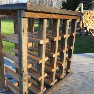 Puede incluir: Estante de vino de madera r&uacute;stica con acabado natural. El estante tiene varios estantes y est&aacute; hecho de madera recuperada.