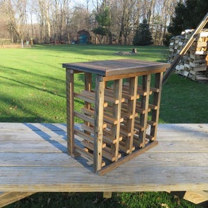 Puede incluir: Un estante de vino de madera r&uacute;stico con un acabado natural. El estante tiene m&uacute;ltiples ranuras para guardar botellas de vino. Est&aacute; sentado en una mesa de madera.