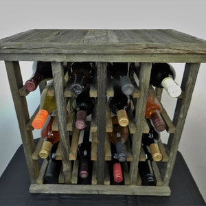 Puede incluir: Un estante de vino de madera r&uacute;stico con un acabado gris desgastado. El estante contiene varias botellas de vino, incluyendo tinto, blanco y rosado.