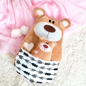 Pu&ograve; includere: Due orsacchiotti di peluche marroni, uno pi&ugrave; grande dell'altro, con cuori ricamati e un motivo a frecce bianche e nere sul tessuto. L'orsacchiotto pi&ugrave; piccolo &egrave; annidato dentro quello pi&ugrave; grande.