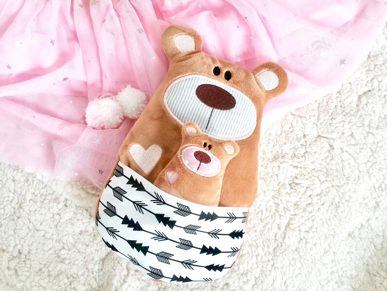 Pu&ograve; includere: Due orsacchiotti di peluche marroni, uno pi&ugrave; grande dell'altro, con cuori ricamati e un motivo a frecce bianche e nere sul tessuto. L'orsacchiotto pi&ugrave; piccolo &egrave; annidato dentro quello pi&ugrave; grande.