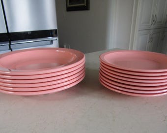 May include: A stack of eight pink plastic dinner plates, and a stack of eight pink plastic salad plates.