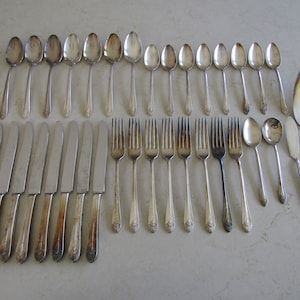 May include: A set of vintage silverware, including forks, knives, and spoons, all in a silver finish. The set includes a serving spoon and a serving knife.