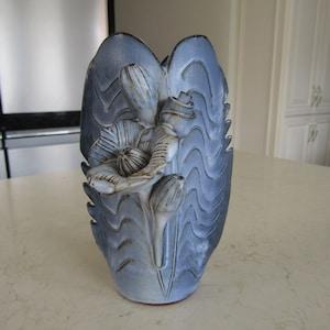 May include: A blue and white ceramic vase shaped like a flower with a textured surface.