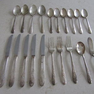May include: A set of vintage silverware, including spoons, forks, and knives. The silverware is made of silver and has a floral design.