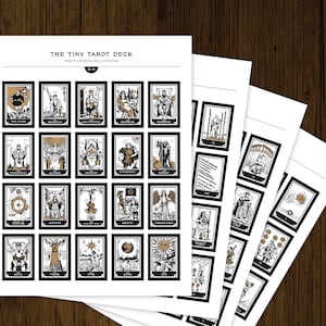 May include: A sheet of black and white tarot card stickers with gold accents. The stickers feature the major arcana cards from the tarot deck. The sheet is titled "The Tiny Tarot Deck Tarot Journaling Stickers".