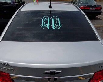 May include: A silver car with a teal monogram sticker on the back window. The sticker says "K.U."