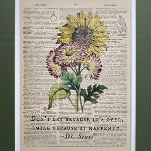 May include: A vintage dictionary page with a colorful floral illustration of sunflowers and pink flowers. The page features the text "Don't cry because it's over, smile because it happened." - Dr. Seuss.