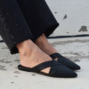 K&ouml;nnte beinhalten: Schwarze Leder-Sandalen mit spitzem Zeh und gekreuztem Riemen.