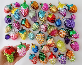 May include: Assortment of vintage glass Christmas ornaments shaped like grapes, berries, and other fruits. The ornaments are in various colors, including red, green, blue, purple, and yellow.