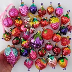 May include: A collection of 35 vintage glass ornaments shaped like various fruits, including grapes, strawberries, and plums. The ornaments are all different colors and have a shiny, reflective finish.