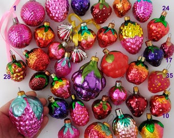May include: A collection of 35 vintage glass ornaments shaped like various fruits, including grapes, strawberries, and plums. The ornaments are all different colors and have a shiny, reflective finish.
