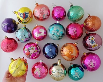 May include: A collection of vintage Christmas ornaments with various designs and colors, including a Santa Claus, a snowman, a duck, and a snowflake. The ornaments are made of glass and have a shiny finish.