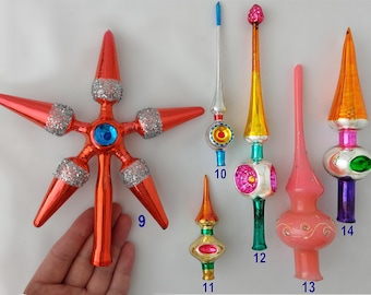 May include: A collection of six vintage glass Christmas tree toppers in various shapes and colors. Item 9 is a large orange star with silver glitter accents. Items 10 through 14 are elongated finials in shades of pink, orange, yellow, and silver.
