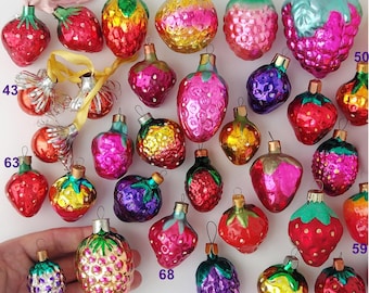 May include: A collection of 20 vintage glass Christmas ornaments shaped like strawberries. The ornaments are in various colors, including red, pink, green, yellow, and blue. Some of the ornaments have a shiny finish, while others have a matte finish.