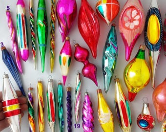 May include: A collection of twenty-eight vintage glass Christmas ornaments in various shapes, including elongated icicles, teardrops, and spheres, featuring vibrant metallic colours like red, green, pink, blue, yellow, and silver with numbered labels.