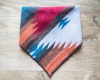 May include: A triangular patterned bandana with a red, orange, blue and grey geometric design.
