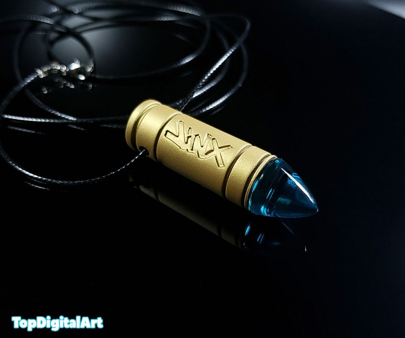 May include: A gold bullet necklace with a blue glass tip. The bullet has the word "Jinx" engraved on it.