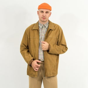 May include: A man wearing a brown suede jacket with a plaid shirt underneath. He is also wearing a bright orange beanie.