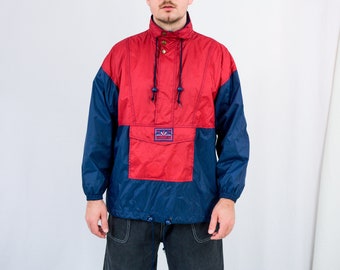 May include: A red and navy blue windbreaker jacket with a zipper and a drawstring hood. The jacket has a large pocket on the front with a logo that says "Wanderlust".