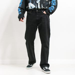 Könnte beinhalten: Schwarze gerade Jeans mit lockerer Passform. Die Jeans haben ein klassisches Fünf-Taschen-Design und einen Knopfverschluss.