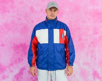 May include: A blue, red, and white color block jacket with a snap closure. The jacket has a hood and two pockets.