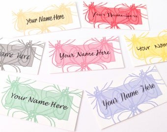 May include: Six blank name cards with different colored floral designs. The text "Your Name Here" is printed on each card.