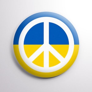 May include: A round button with a peace sign in white on a blue and yellow background, representing the Ukrainian flag.