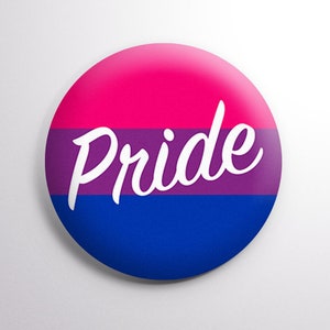 May include: A round button with the bisexual pride flag colors: pink, purple, and blue. The word "pride" is written in white cursive across the middle of the button.