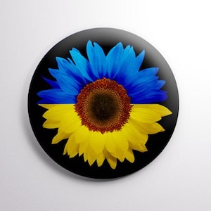 May include: A sunflower with blue petals and a yellow center on a black background. The sunflower is a symbol of hope and peace.