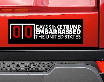 May include: A red car with a bumper sticker that reads "00 Days Since Trump Embarrassed The United States".