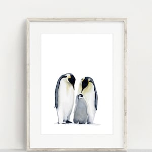 May include: Watercolor print of a penguin family. Two adult penguins stand on either side of a smaller, gray penguin chick. The penguins are depicted in shades of black, white, and gray, set against a white background, framed in a light wood frame.