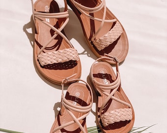 May include: Three pairs of pink woven sandals with adjustable ankle straps. The sandals have a brown sole and are arranged in a size order from largest to smallest.