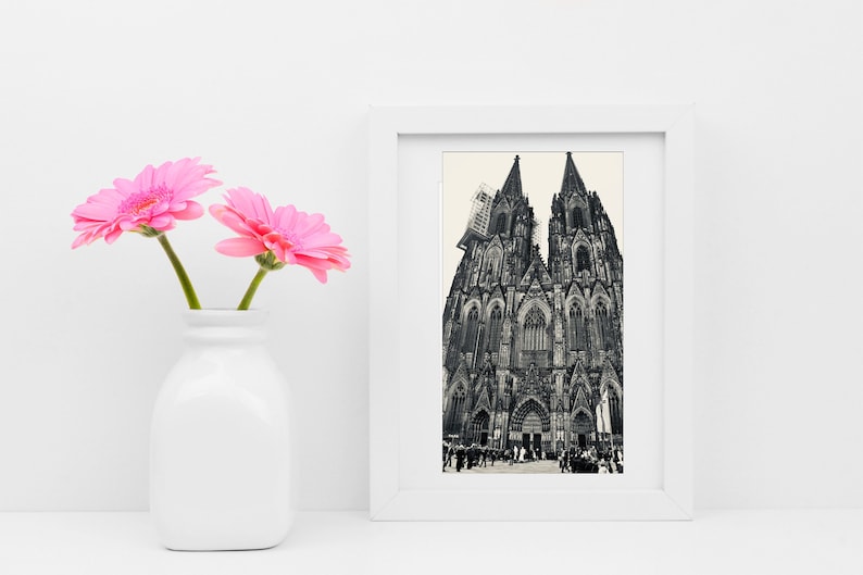 K&ouml;nnte beinhalten: Ein Schwarzwei&szlig;foto des K&ouml;lner Doms in Deutschland, gerahmt in einem wei&szlig;en Rahmen. Das Foto ist an einer wei&szlig;en Wand mit rosa Blumen in einer wei&szlig;en Vase ausgestellt.