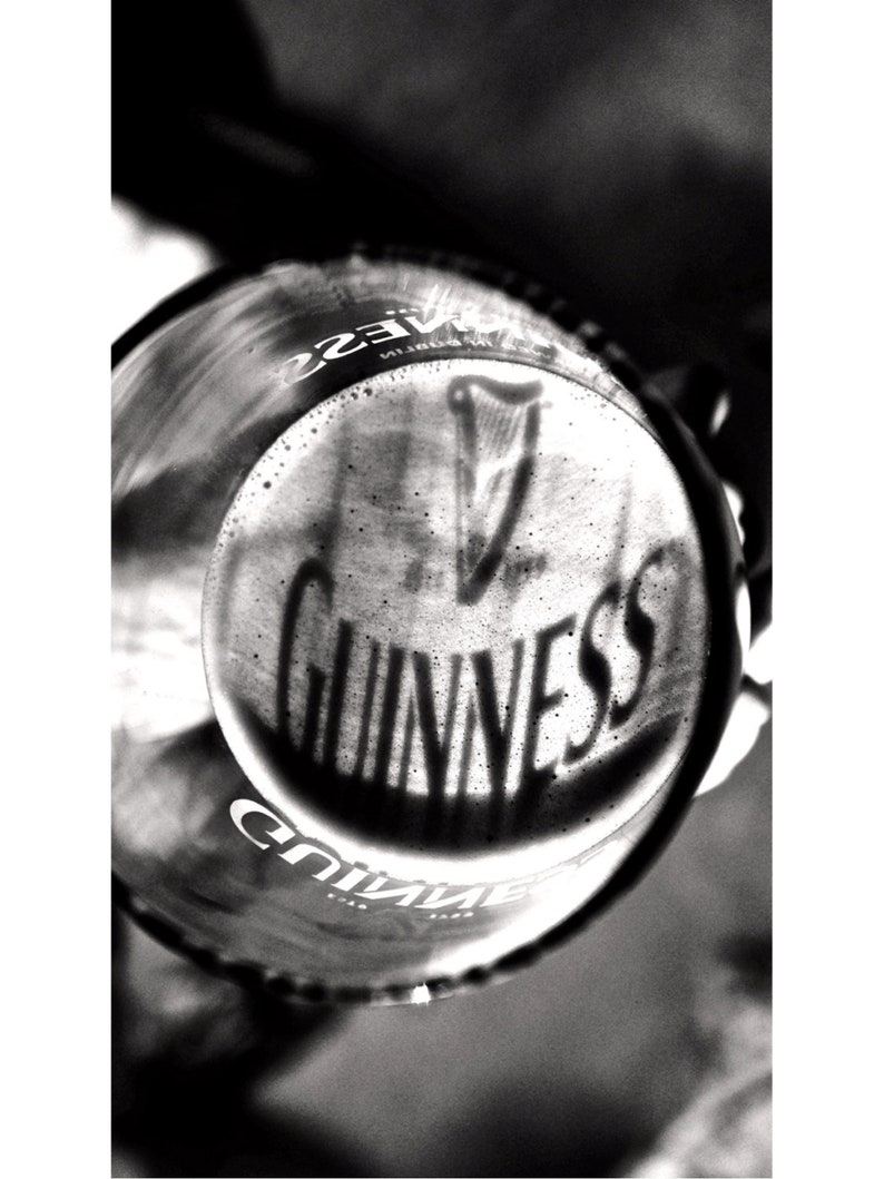 May include: A close-up of a glass of Guinness beer with a thick head of foam. The Guinness logo is visible in the foam.