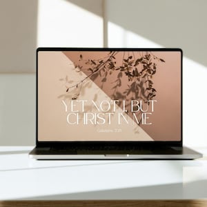 May include: A laptop computer with a beige and white background. The screen displays a quote in white text: "Yet not I, but Christ in me." The quote is attributed to Galatians 2:20.