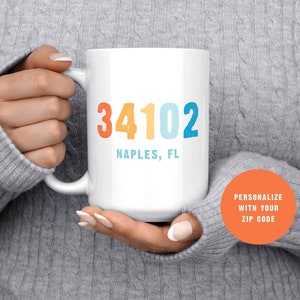 May include: White ceramic mug with a colorful design featuring the zip code "34102" and the text "Naples, FL".