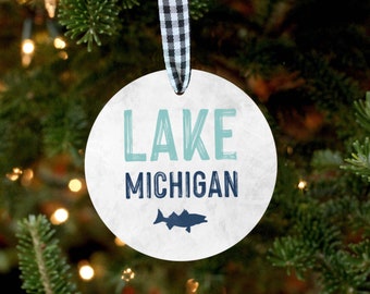 May include: White round Christmas ornament with the text "LAKE MICHIGAN" in blue and teal lettering. A silhouette of a fish is below the text.