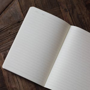 May include: An open lined notebook with a blank page on a wooden surface. The notebook has a section for the date and page number.