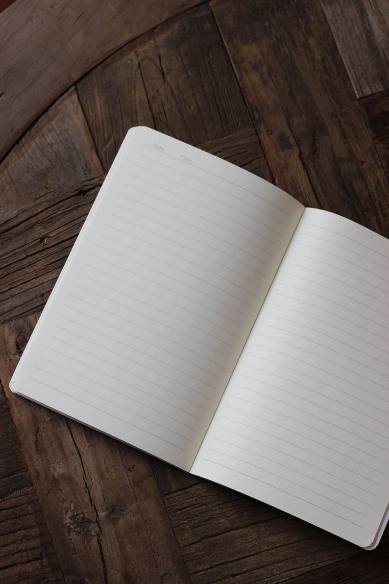 May include: An open lined notebook with a blank page on a wooden surface. The notebook has a section for the date and page number.