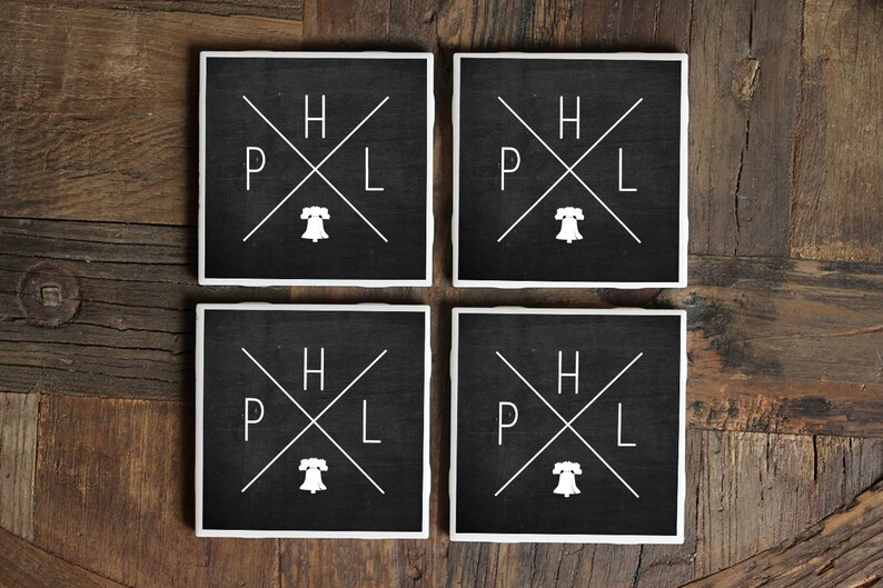 May include: Set of four black square coasters with white lettering and a Liberty Bell graphic. The coasters feature the letters "H", "P", "L" arranged in a cross pattern.