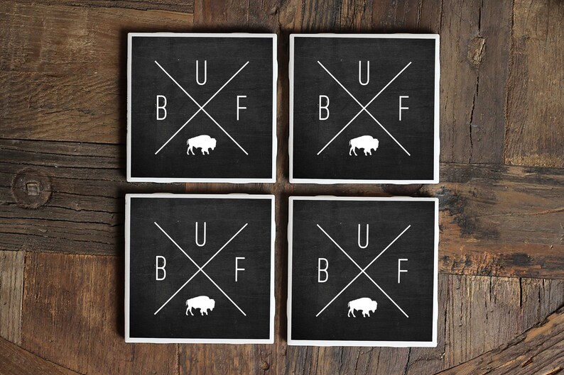 May include: Set of four black square coasters with white lettering and a white buffalo silhouette. The coasters read "B U F F" with the letters arranged in a cross pattern.
