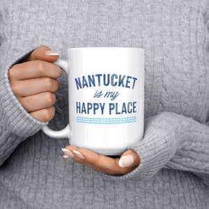 May include: White ceramic coffee mug with blue text that reads "NANTUCKET is my HAPPY PLACE" with a blue wavy line design below the text.