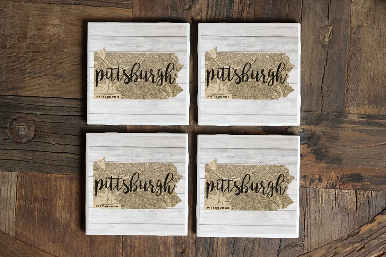 May include: Set of four white ceramic coasters featuring a vintage map of Pittsburgh, Pennsylvania, with the word "pittsburgh" in black script.